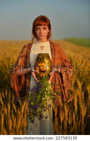 red hair girl whit violet flowers in the wheat field