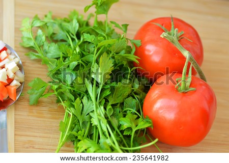 Fresh growing flat leaf parsley background, tomatoes and vegetables