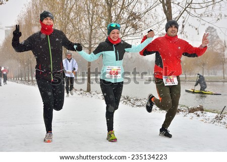BUCHAREST, ROMANIA - DECEMBER 1st: Happy unidentified marathon runners compete while snowing, at the National Day of Romania Marathon 2014, December 1st, 2014 in Bucharest, Romania