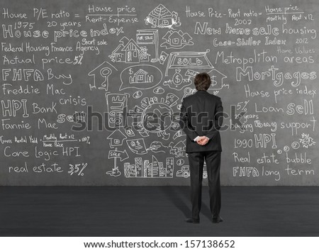 Businessman thinking about home sales standing in front of a grey wall 2