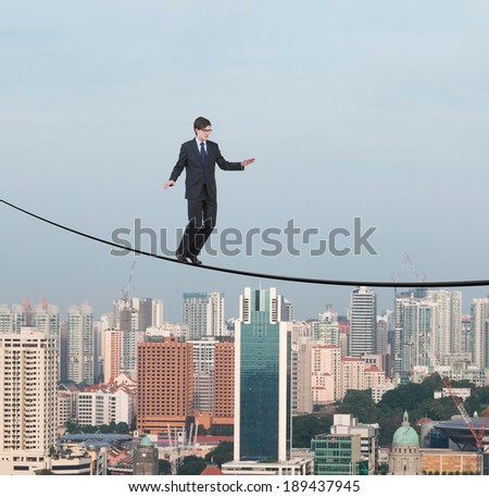 Balancing businessman, rope, city.