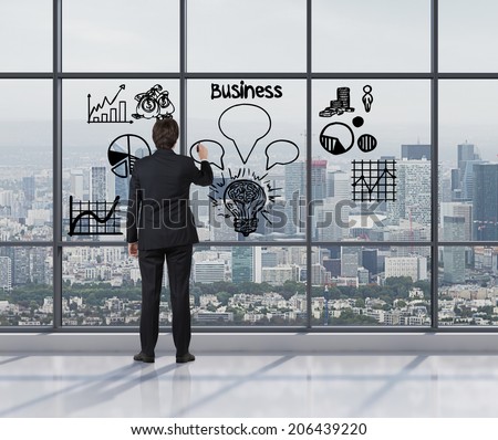 Young businessman drawing a set of the graphs including pie chart, line graph and sketches in a glass screen.