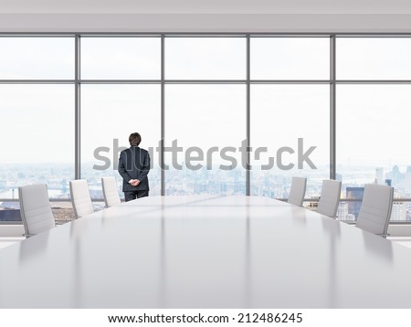 Thinking businessman in a Conference room. Modern office with windows and city view.