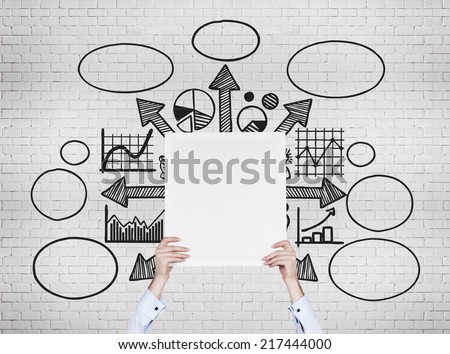 Thinking businessman in front of a set of the graphs including pie chart, line graph and sketches. Holding a white empty banner.
