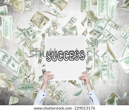 Businessman holding a poster \'success\' while dollar\'s bills are falling from the sky.