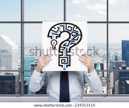 Businessman is holding a banner with the Maze in a shape of Question mark. City view background.