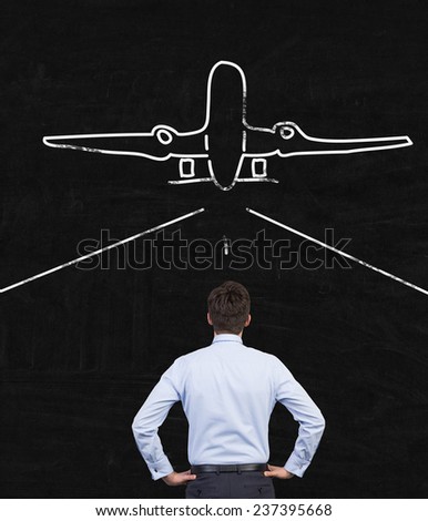 businessman looking at drawing airplane on gray wall background