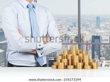 businessman standing in office and heap gold coins on table