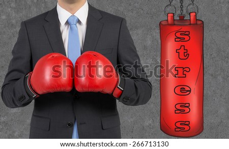 Young businessman in a suit wearing boxing gloves is ready to hit the punching bag