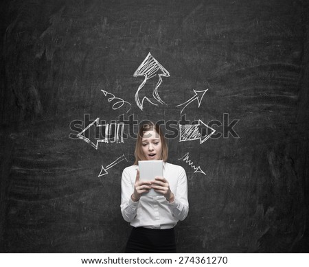 Young business lady is looking at the tablet. Arrows are symbolised different ideas. Chalk wall background.