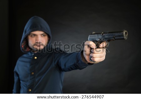 Armed man in a hoodie is pointing a handgun at the target.