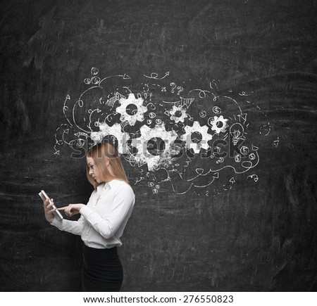 Young beautiful business woman is thinking about business optimisation process by working on the tablet. Drawn business flowchart on the concrete wall.