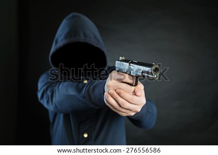 Armed person in a hoodie is pointing a handgun at the target.