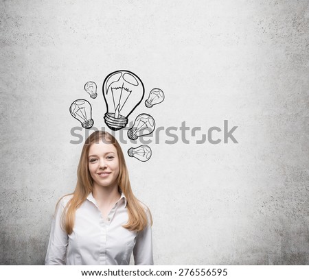 Smiling young beautiful business lady is thinking about new innovative ideas. Light bulbs are drawn on the concrete wall behind the lady.