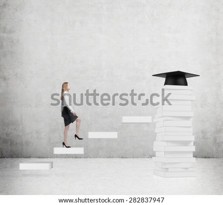 Young lady is going up to graduate university. Graduation hat as a prize at the end of the educational process. Concrete background.