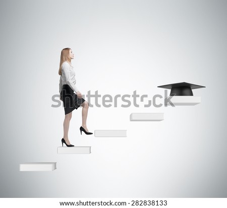 Young lady is going up to graduate university. Graduation hat as a prize at the end of the educational process. Concrete background.