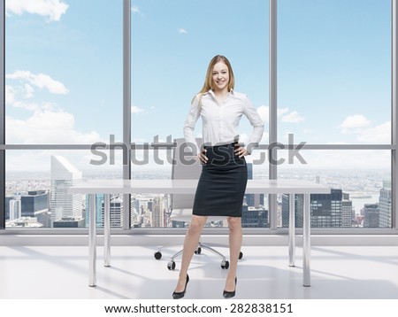 Beautiful smiling employee is standing in the office with New York panoramic view. A concept of the modern workplace.