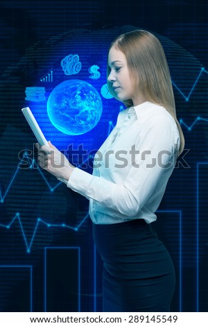 A lady is holding a digital document with hologram projection of the content. Globe, dollar sign and charts.