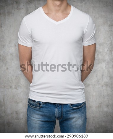 Close up of the body view of the man in a white t-shirt. Hands are crossed behind the back. Concrete background.