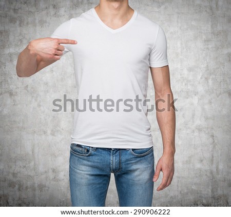 Close-up of a man pointing his finger on a blank t-shirt. Concrete background.