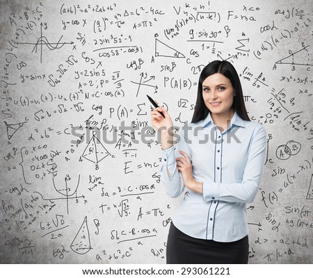 Portrait of smiling woman who points out complicated math calculations. Math formulas are written on the concrete wall.