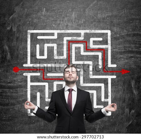 Meditative businessman and solved labyrinth with a red arrow on the black chalk board.