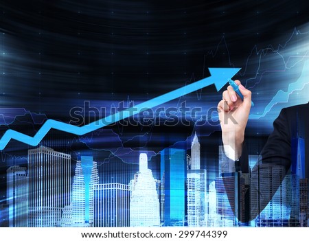 A hand is drawing a growing arrow on the glass screen. A concept of financial business services. Hologram of the cityscape.