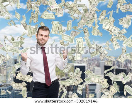 Closeup portrait of happy successful businessman who close the deal, fists pumped. A concept of celebrating the success. Dollar note are falling down over the business city.