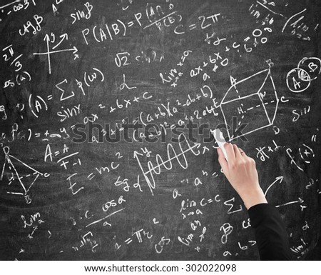 A woman\'s hand is writing math calculations on black chalk board. Analyst.