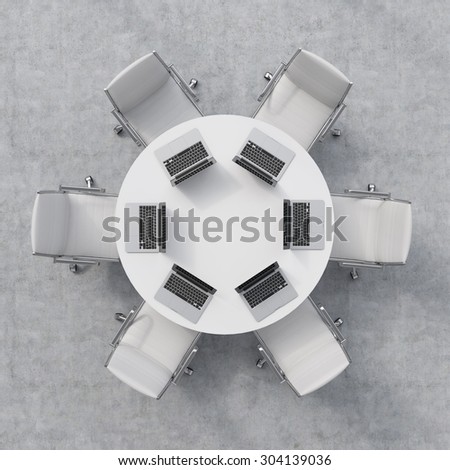 Top view of a conference room. A white round table, six chairs. Six laptops are on the table. Office interior. 3D rendering.