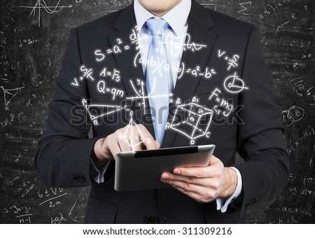 Young man in formal suit is holding a tablet with math formulas projection on the air.