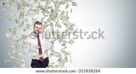 Happy successful manager or businessman is getting benefits from his job. Dollar note are falling down from the ceiling. Concrete background.