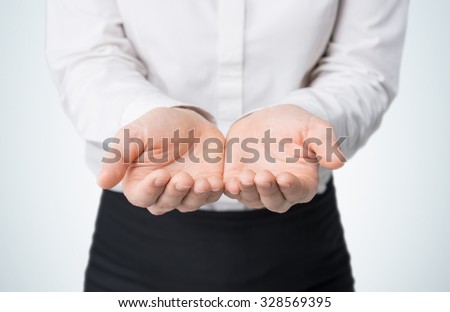 Close-up of woman\'s hands, palms up. A woman dressed in formal clothes. A light blue background.