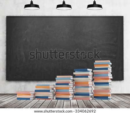 A stair is made of colourful books. Black chalk board, three black ceiling lights, wooden floor and concrete wall are in the room.