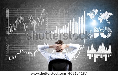 Research concept with businessman sitting in front of wall with forex charts