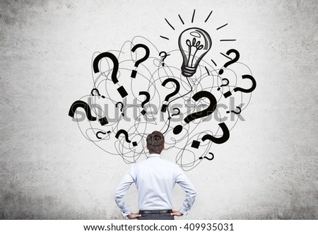 Idea concept with businessman facing question mark and bulb sketch on concrete wall