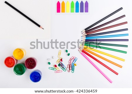 Colorful pencils, gouache paint, stickers, clips and pins on white background