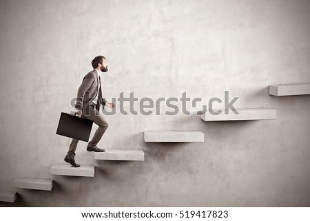 Side view of a man climbing the stairs built in a blank concrete wall. Concept of success and achieving your goal. Mock up