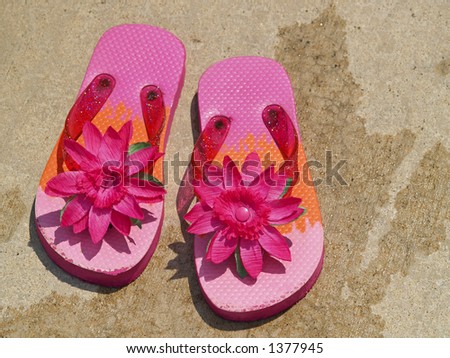 pink flip flop sandals on wet cement surrounding a swimming pool