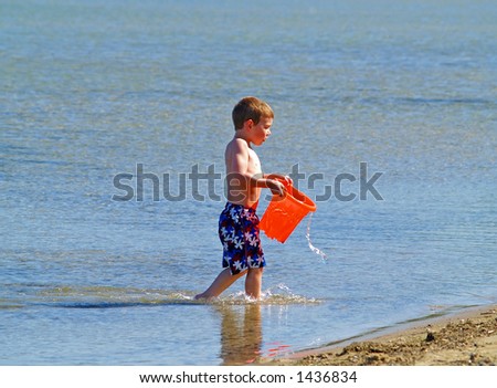 boy carrying a bucket of water at the beach