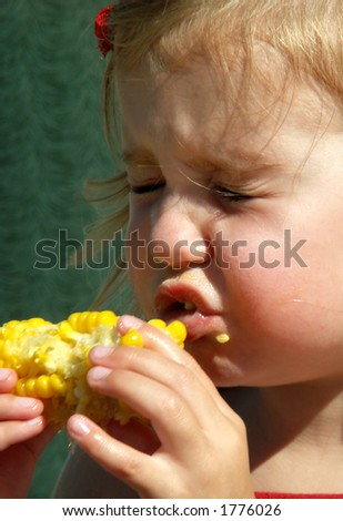 little girl with eyes shut after being sprayed by juicy corn on the cob