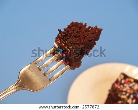bite of cake on a fork with more cake in on a plate in the background