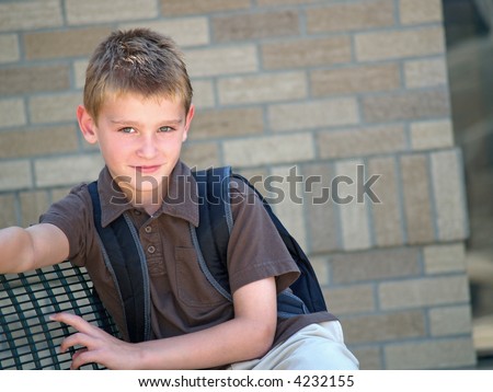 young boy sitting on a bench and waiting for the school bus