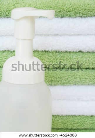 foaming handsoap in front of a stack of bath towels - focus on bubbles