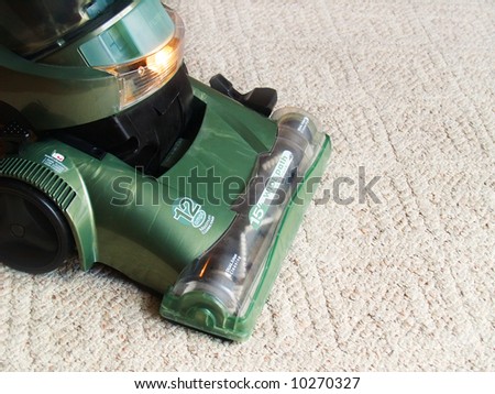 a green vacuum cleaner sweeping the carpet