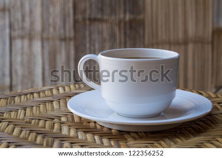 Cup of hot coffee on Rattan table