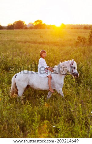 Little girl riding a horse in a field