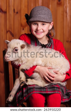 A child sits on a chair and on her lap favorite lamb On the farm