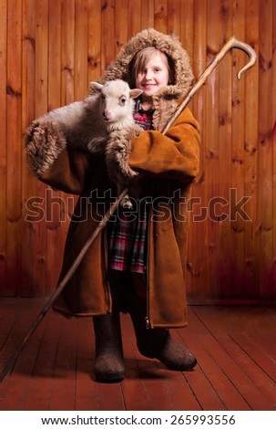 Playful girl shepherd with his staff under his arm a lamb on the farm