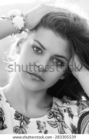 Black and white portrait of a cheerful girl pulls her hands up in her hair